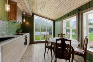 a kitchen with a table and chairs and windows at Flatheim in Viksdalen