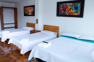 a group of three beds in a room at La Gran Estancia Hotel Campestre in Chachagüí