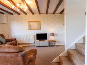 a living room with a couch and a television at Oak Leaves Cottage in Newton Abbot