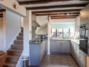 a kitchen with white cabinets and a staircase at Oak Leaves Cottage in Newton Abbot