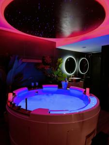 a hot tub in a room with pink lighting at La loveroom bdsm de Nice " la chambre luxe des désirs " in Nice