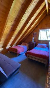 a attic room with two beds and a window at Hermosa casa en Condominio in Pucón