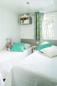 Duas camas num quarto com um urso de peluche sentado em cima em Camping le Rancho em Argelès-sur-Mer