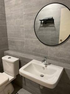 a bathroom with a toilet and a sink and a mirror at MyHome @ Riverine Resort Kuching in Kuching
