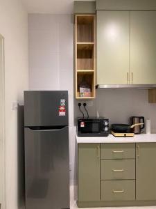 a kitchen with a refrigerator and a microwave at MyHome @ Riverine Resort Kuching in Kuching