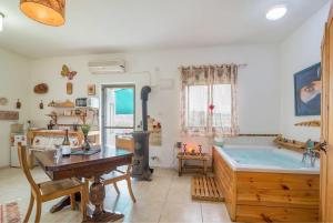 a room with a bath tub and a table and a wooden desk at SHIR HACHORESh in Shomera