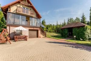 een groot huis met een patio en een terras bij Domek nad jeziorem in SzczybaÅ‚y OrÅ‚owskie