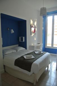a bedroom with a large bed with blue walls at Hotel Danemark in Nice