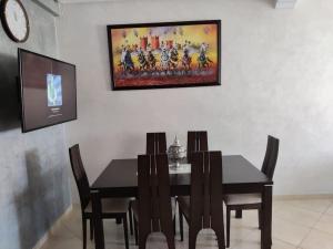 a dining room table with chairs and a painting on the wall at Appartement très proche Rabat et de l'Aéroport in Salé