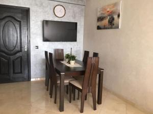 a dining room table with chairs and a clock on the wall at Appartement très proche Rabat et de l'Aéroport in Salé