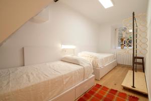 a white bedroom with two beds and a window at Aittitta Makurra etxea in Lekeitio