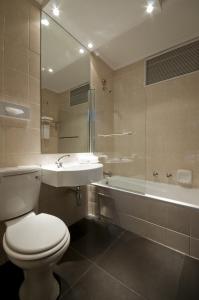a bathroom with a toilet and a sink and a tub at Manhattan Hotel in Pretoria