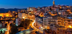 una città illuminata di notte con edifici di Next b&b a Frosinone