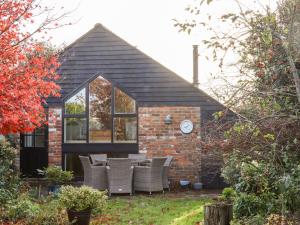a brick house with chairs and a clock on it at Tillingham View in Rye