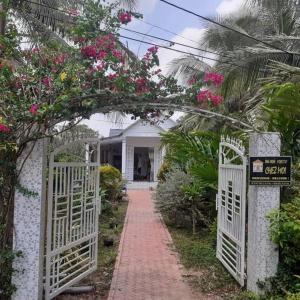 a walkway leading to a white house with pink flowers at Homestay Chez Moi in Can Tho