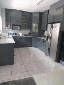 a kitchen with gray cabinets and a refrigerator at Vaal holiday home in Vanderbijlpark