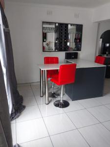 a kitchen with red chairs and a counter with wine bottles at Vaal holiday home in Vanderbijlpark