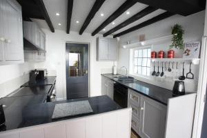 a kitchen with white cabinets and black counter tops at 1 Bodwen Villas in Llangollen