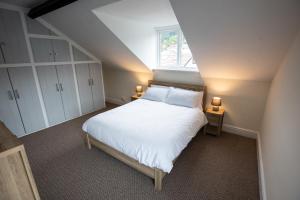a bedroom with a bed with white sheets and a window at 1 Bodwen Villas in Llangollen