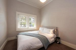 1 dormitorio con cama blanca y ventana en Renovated 3 Bedroom Family Home in Richmond with Parking, en Melbourne