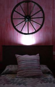 aokedoked wheel hangs above a bed with a pink wall at Casa Rural El Pajar de Puchero in Ruidera