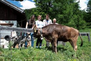 Un groupe de personnes debout à côté d'une vache dans l'établissement Hotel Chalet Genziana, à Peio