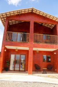 a red brick building with a balcony and two chairs at Chale c churrasqueira a 5 min da Praia de Pipa RN in Pipa