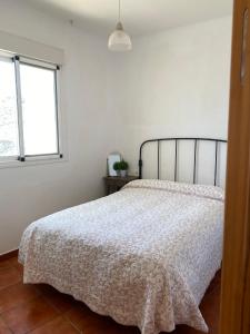 a bedroom with a bed with a white bedspread and a window at Casa Alma in Almería