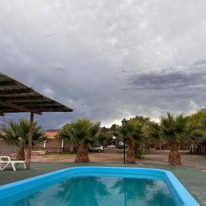 a blue swimming pool with palm trees and a cloudy sky at Hotel Valle Colorado in Villa Unión