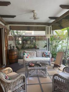 ein Wohnzimmer mit einem Sofa und Stühlen auf einer Terrasse in der Unterkunft Chez Henri in Pointe d'Esny