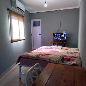 1 dormitorio con cama, mesa y TV en Hostal Lo de Ramona en Belén