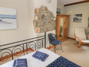 a bedroom with a bed and a chair and a stone wall at 2 Yr Hen Felin in Haverfordwest