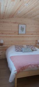 a bedroom with a bed in a wooden cabin at Les Roulottes des Ris in Vallon-en-Sully