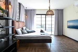Un dormitorio con una cama y una ventana grande. en הודולה - וילות נדירות עם בריכות מחוממות פרטיות ונוף מושלם לכנרת, en Giv'at Yo'av