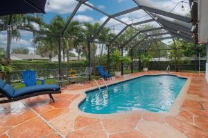 a swimming pool with a pergola and a patio with blue chairs at Three Bedroom Pool Home with Modern Interior Design in Coral Springs