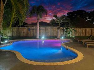 uma piscina à noite com palmeiras em Delilas Chic 3 Bedroom 2 bath Abode with Heated Pool em Deerfield Beach