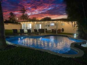 uma piscina em frente a uma casa com um pôr-do-sol em Delilas Chic 3 Bedroom 2 bath Abode with Heated Pool em Deerfield Beach
