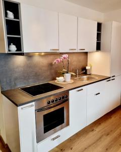 a kitchen with white cabinets and a stove top oven at Appartements Falkner in Roppen