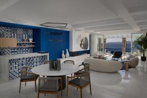 a living room with blue walls and a table and chairs at Mykonos Grand Hotel & Resort in Agios Ioannis Mykonos