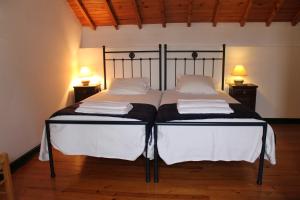 a bedroom with two beds with white sheets and two lamps at Casa de Viana do Alentejo in Viana do Alentejo