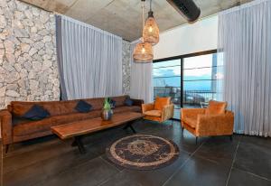 Una sala de estar con un sofá y dos sillas y una mesa. en הודולה - וילות נדירות עם בריכות מחוממות פרטיות ונוף מושלם לכנרת, en Giv'at Yo'av