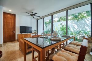 uma sala de jantar com uma mesa e cadeiras e uma televisão em Omara 2-BR Pool · Tropical 2-BR Condo With Private Pool + Amenities! em Tulum