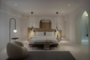 a bedroom with a large white bed and a chair at Mykonos Grand Hotel & Resort in Agios Ioannis Mykonos