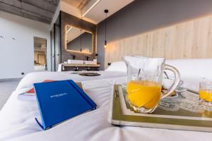 uma bandeja com um copo de sumo de laranja e um livro sobre uma cama em Hospedium Hotel Devalar Do Mar em Camariñas