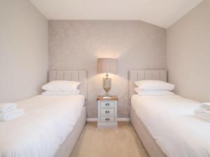 two twin beds in a bedroom with a lamp on a night stand at Woodbridge Penthouse in Woodbridge