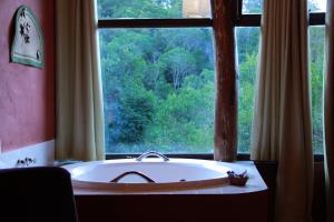 a bath tub in a room with a large window at Alive Eco Hut Pousada in Monte Verde