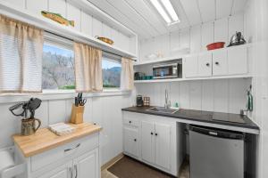 cocina con armarios blancos, fregadero y lavavajillas en Indian Creek Lodge, en Douglas City