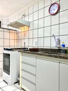 una cocina con armarios blancos y un reloj en la pared en Apto charmoso na V Planalto perto Shopping com 2 Quartos ArCond Wifi Fibra Home Office e Garagem em Dourados, en Dourados