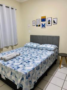 a bed with a blue and white comforter in a bedroom at Apto charmoso na V Planalto perto Shopping com 2 Quartos ArCond Wifi Fibra Home Office e Garagem em Dourados in Dourados