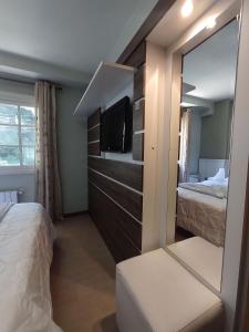 a bedroom with two beds and a tv and a mirror at Charmoso, Junto ao Mini Mundo, para sair e deixar o carro na Garagem. in Gramado